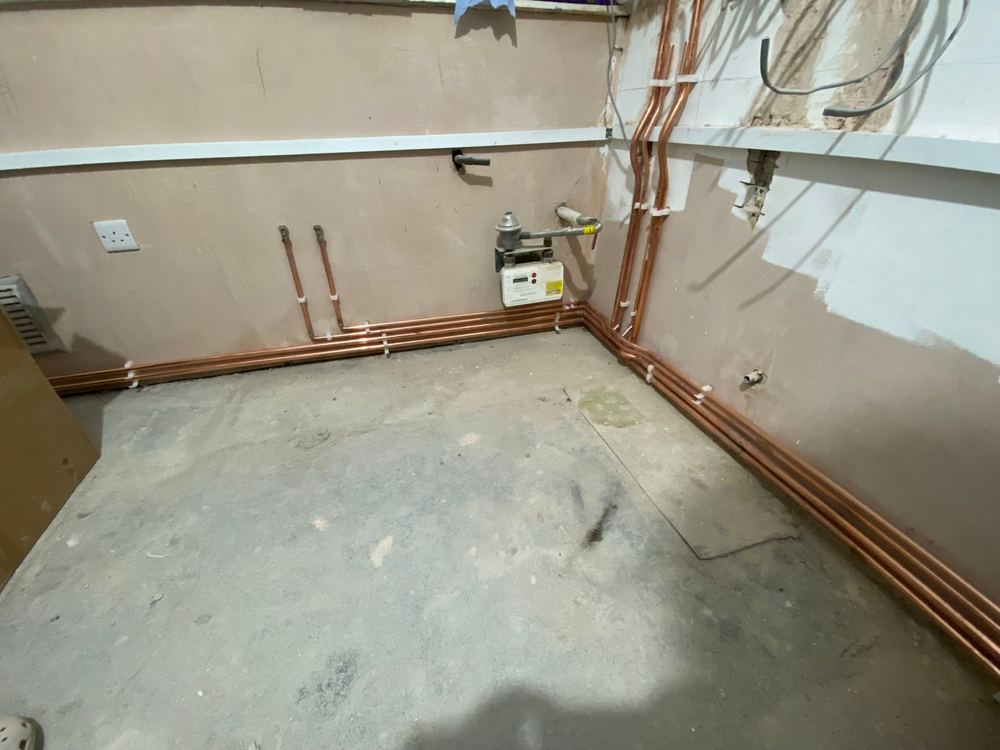 New copper heating pipework run neatly along the skirting during a central heating installation