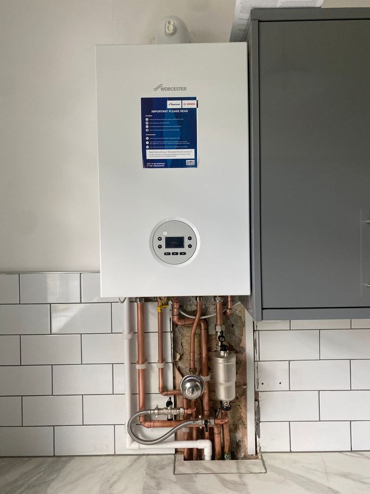 New Worcester Bosch combi boiler installed by Bronze Plumbing & Heating with neat copper pipework and a magnetic system filter